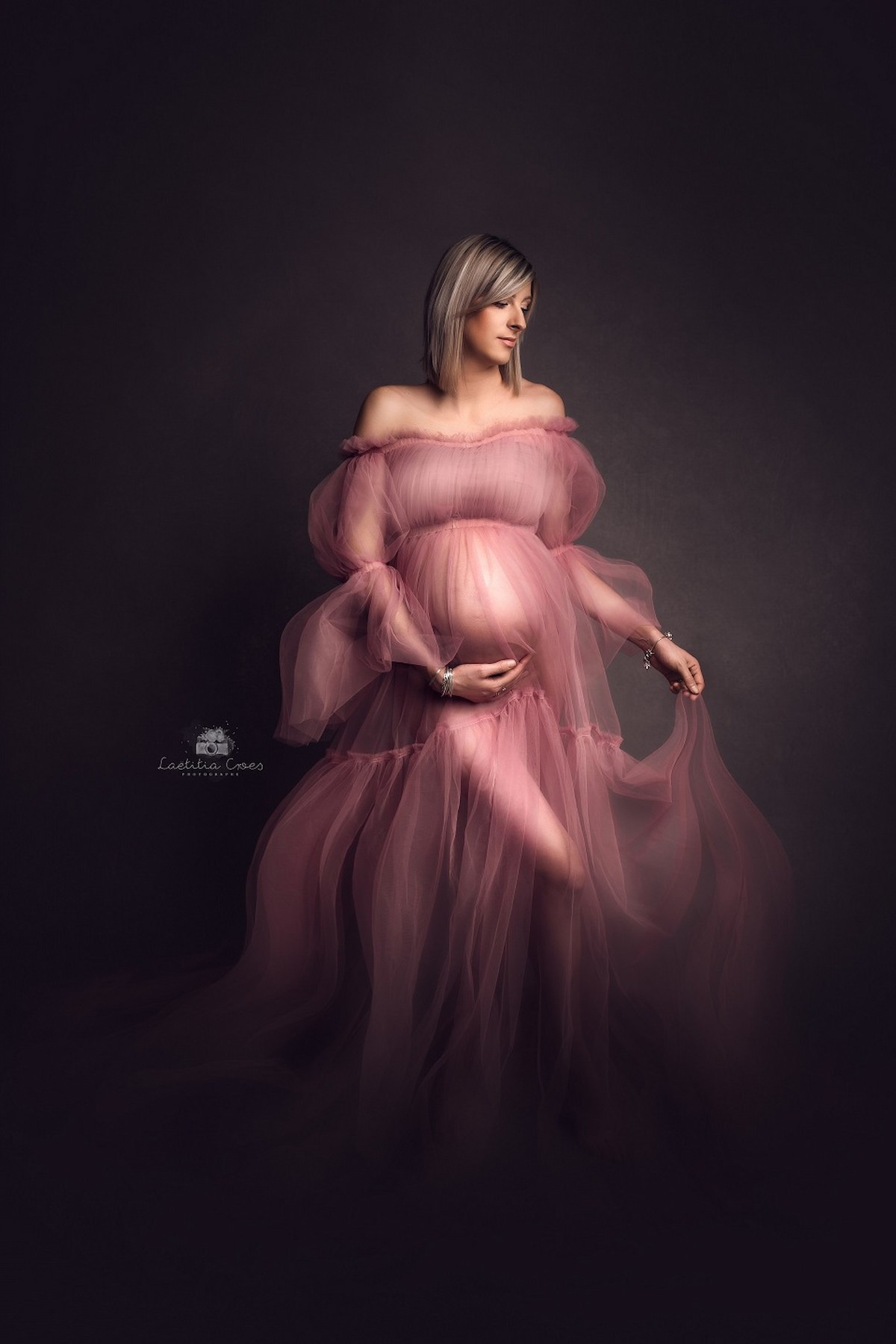 pregnant woman wearing blush pink tulle maternity gown studio portrait
