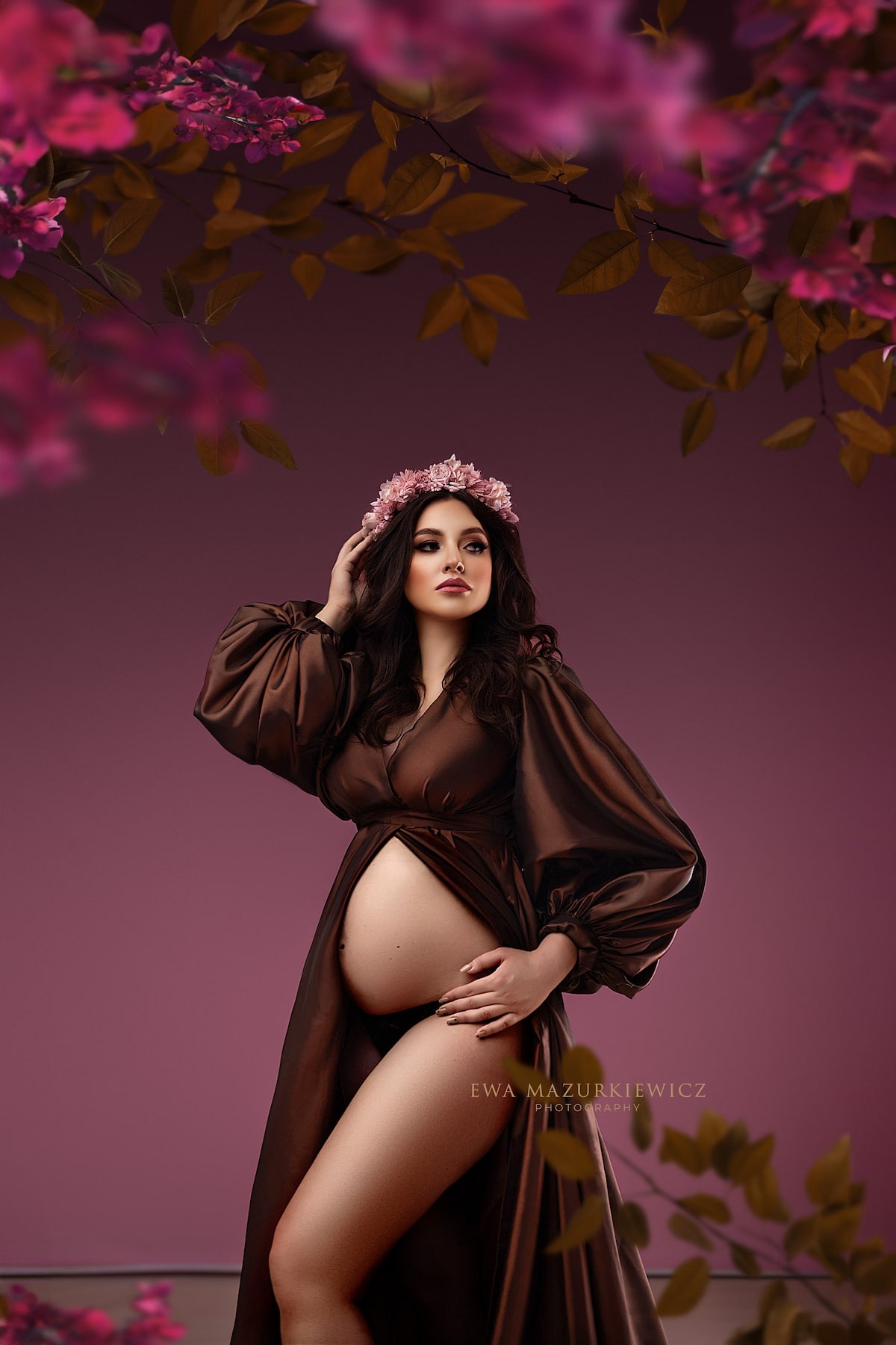 Pregnant woman in elegant wrap dress with voluminous sleeves and floral headpiece, studio photography