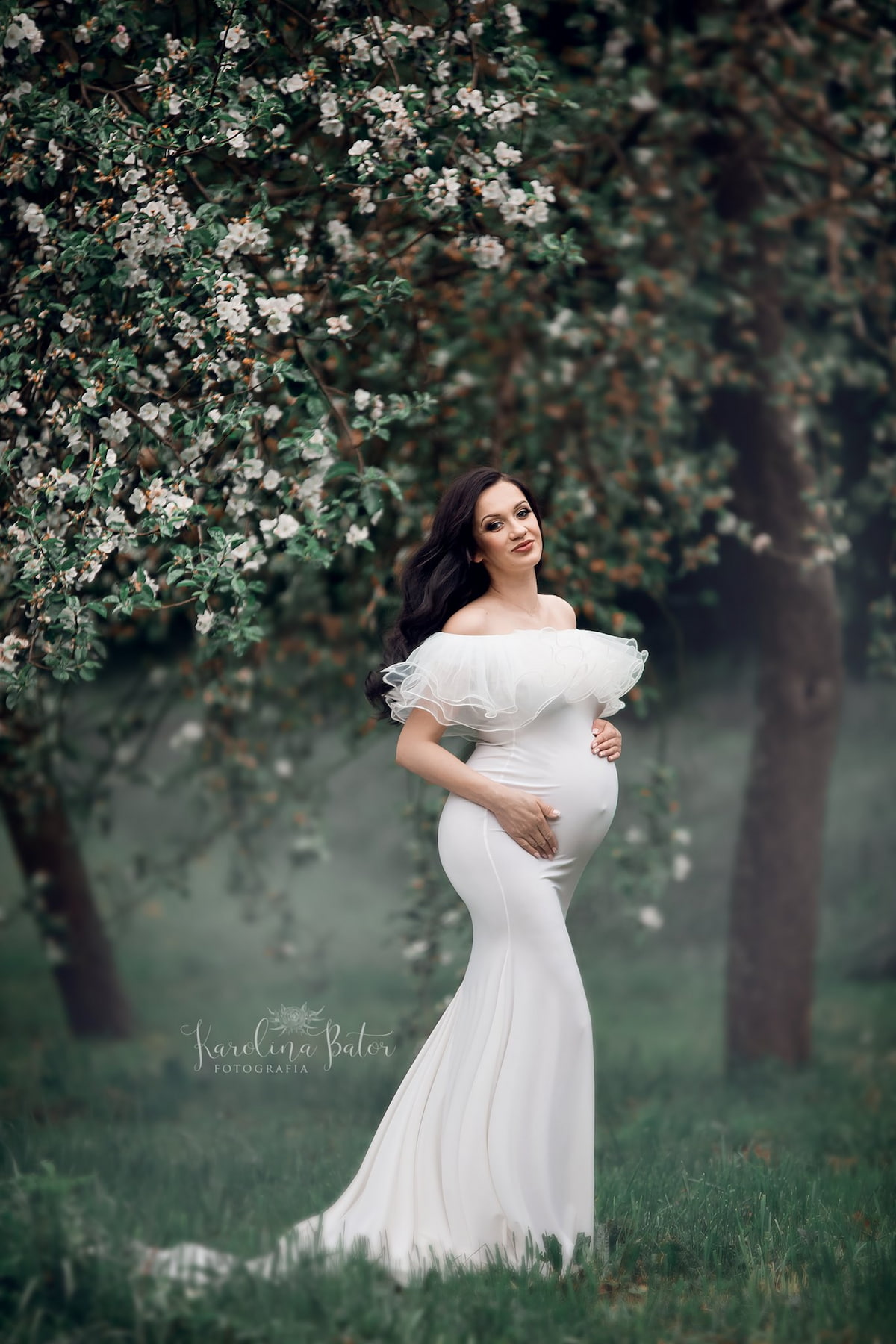 Pregnant woman in mermaid style dress with soft tulle neckline in blooming garden