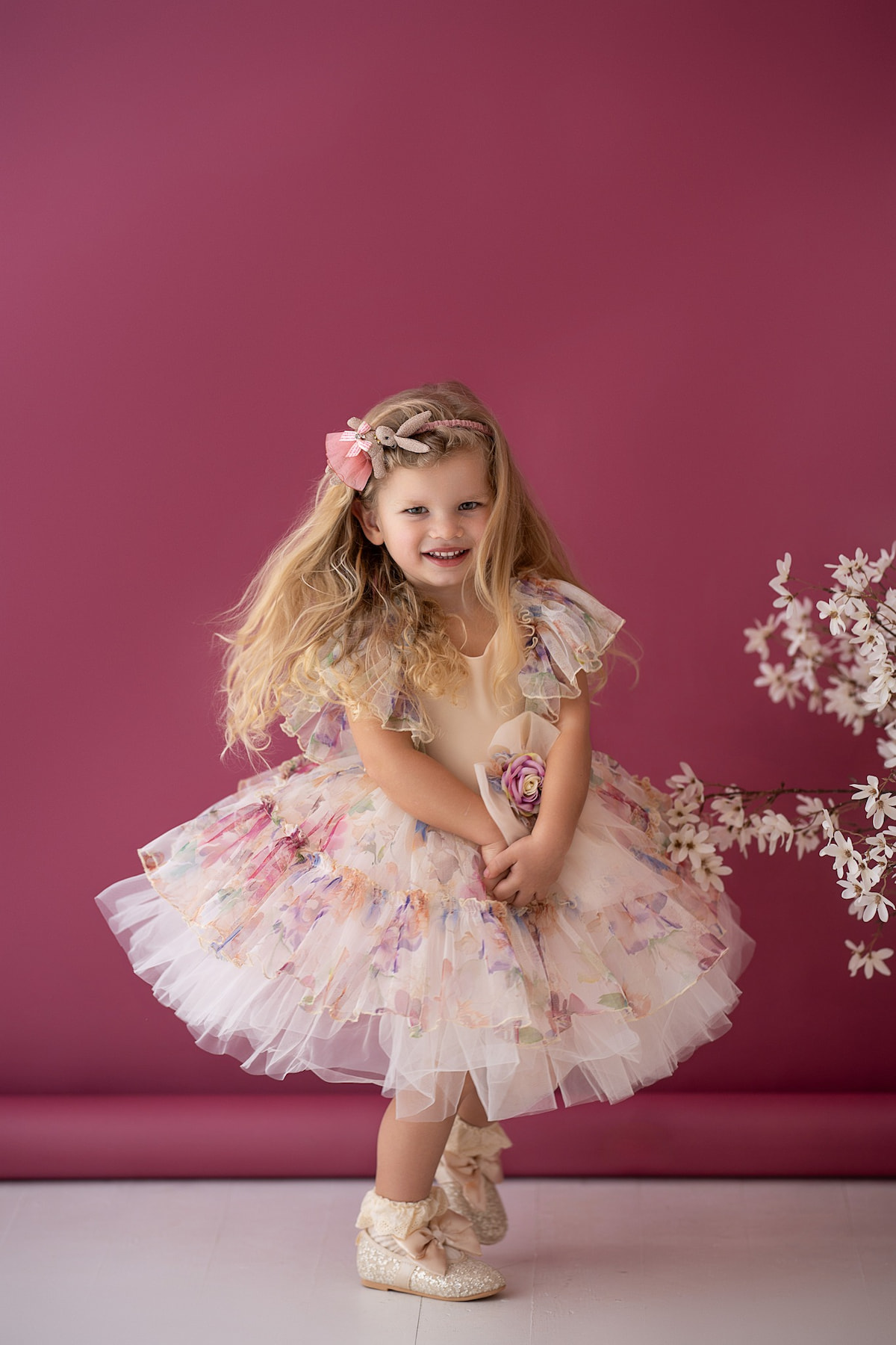 Child in a layered tulle dress with floral print and decorative waist flower