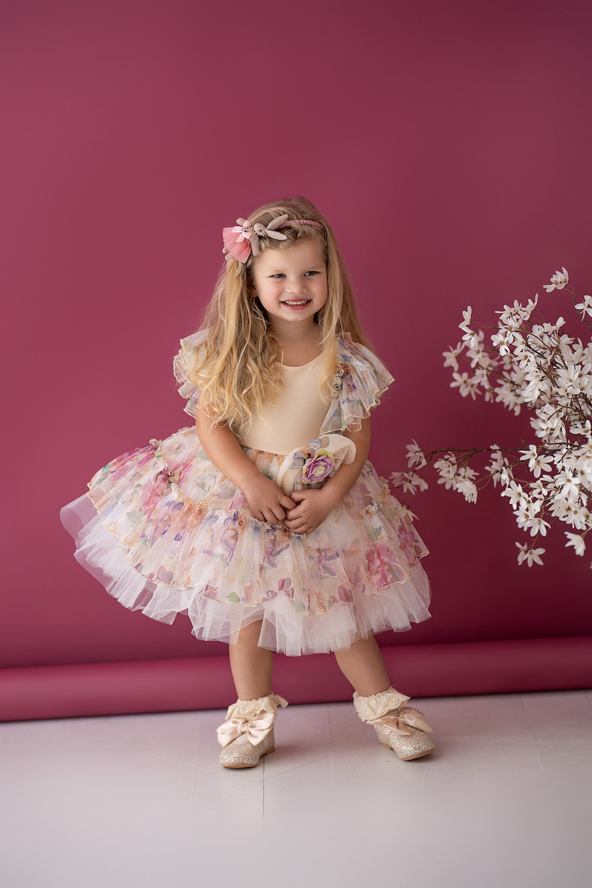 Child in a layered tulle dress with floral print and decorative waist flower