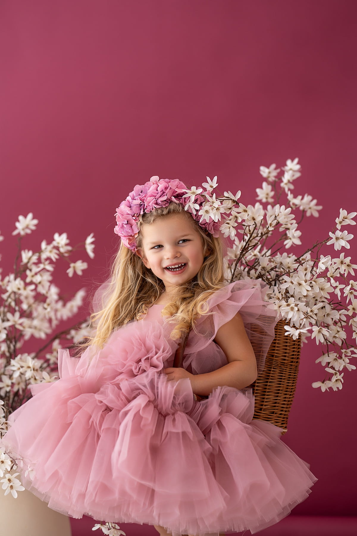 Little girl in a layered tulle dress holding the skirt in a photoshoot