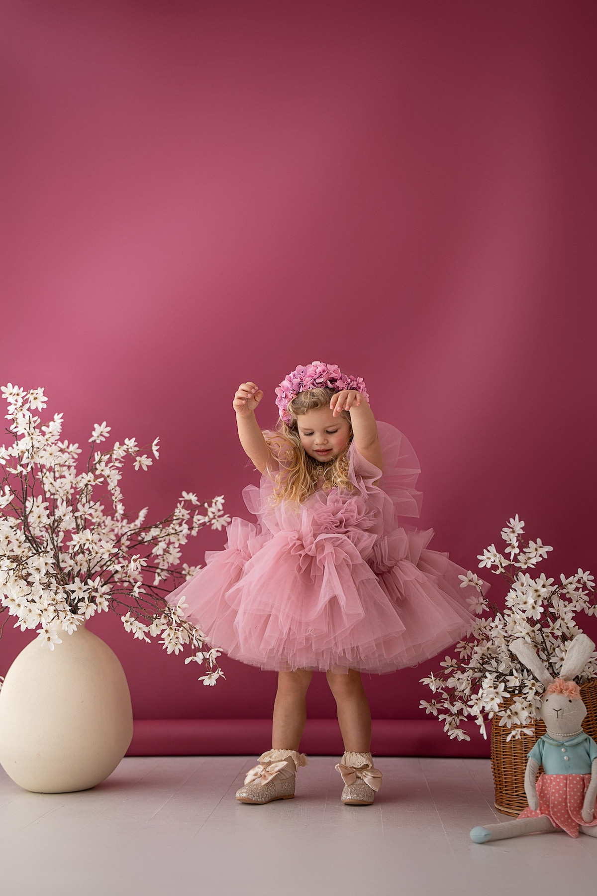 Child in a voluminous tulle dress with flowers and studio props