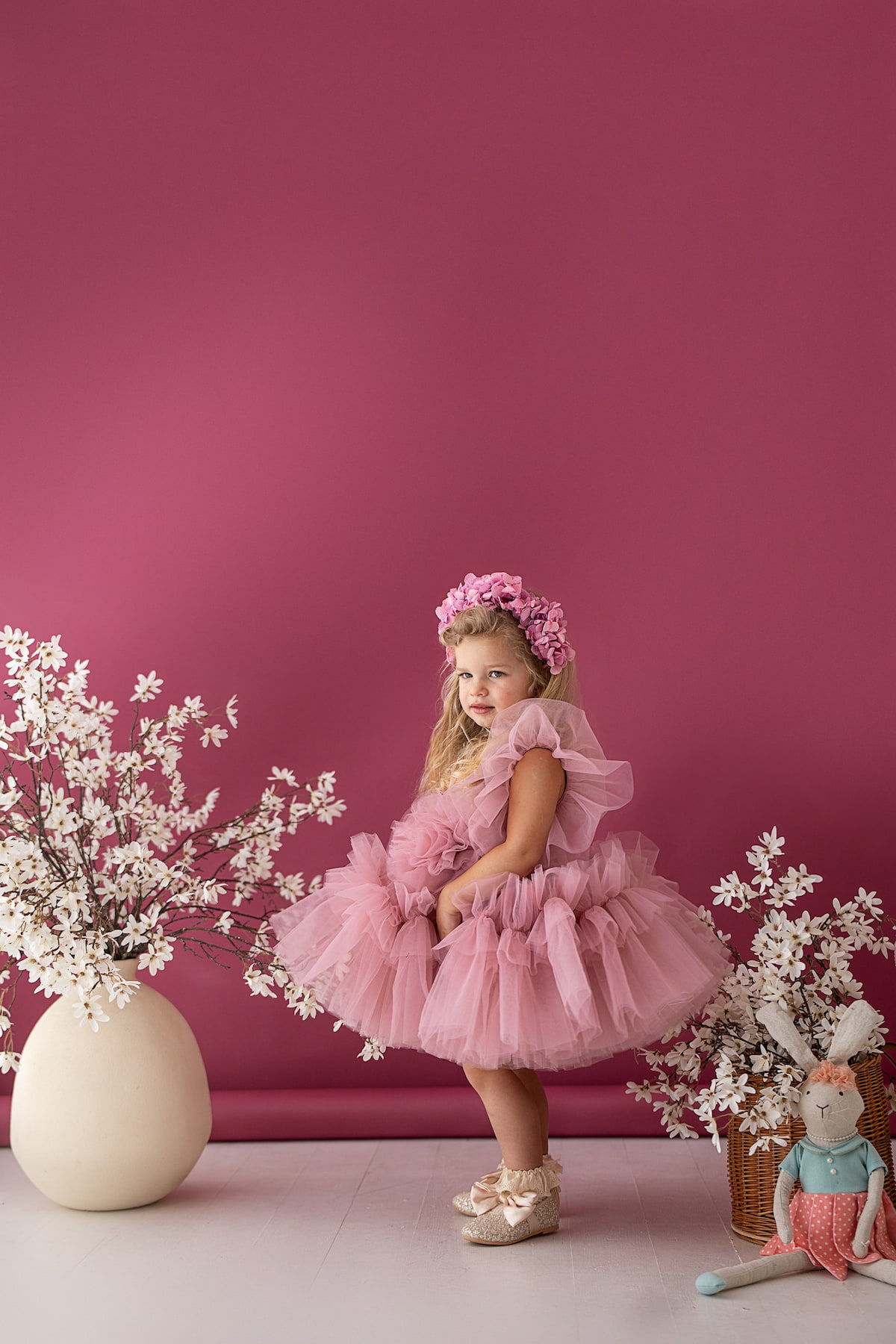 Girl in a pink tulle dress posing with a basket of flowers