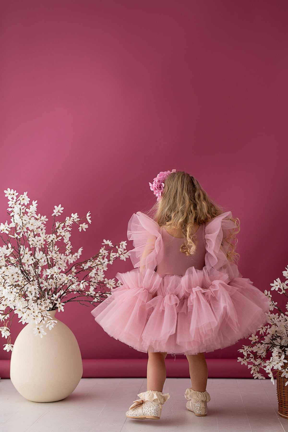 Back view of a child wearing a layered tulle dress in a studio setting