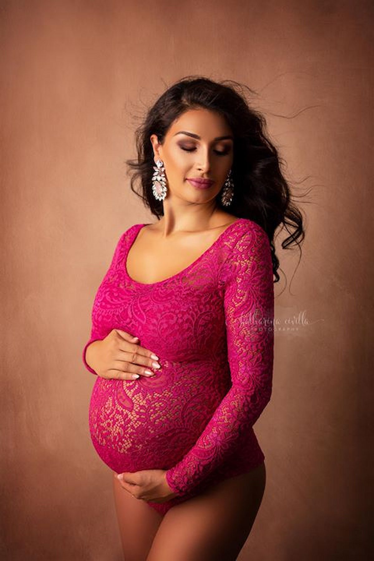 Pregnant woman in pink lace Laura bodysuit, elegant studio maternity photoshoot