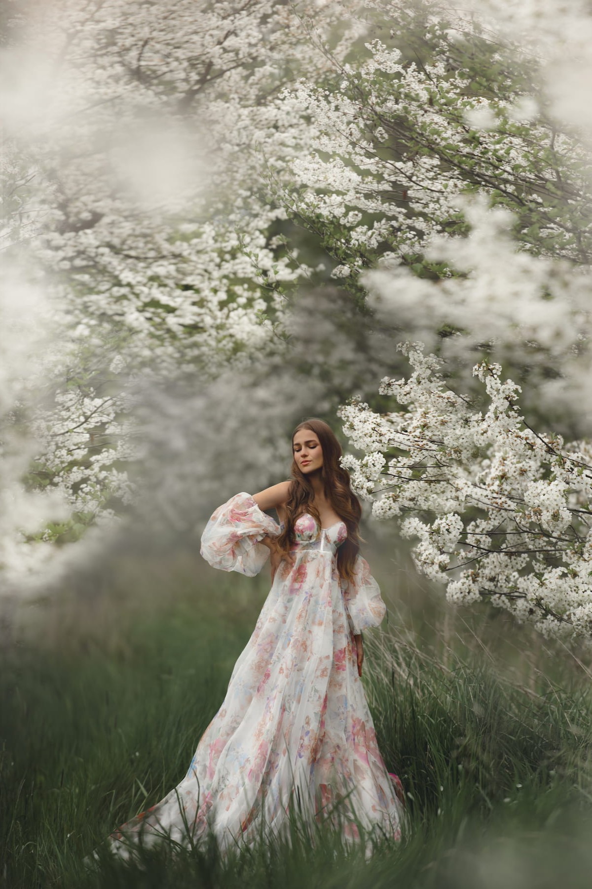 Rosa maternity dress with floral print and airy tulle fabric, captured in outdoor spring photoshoot among blossoms.